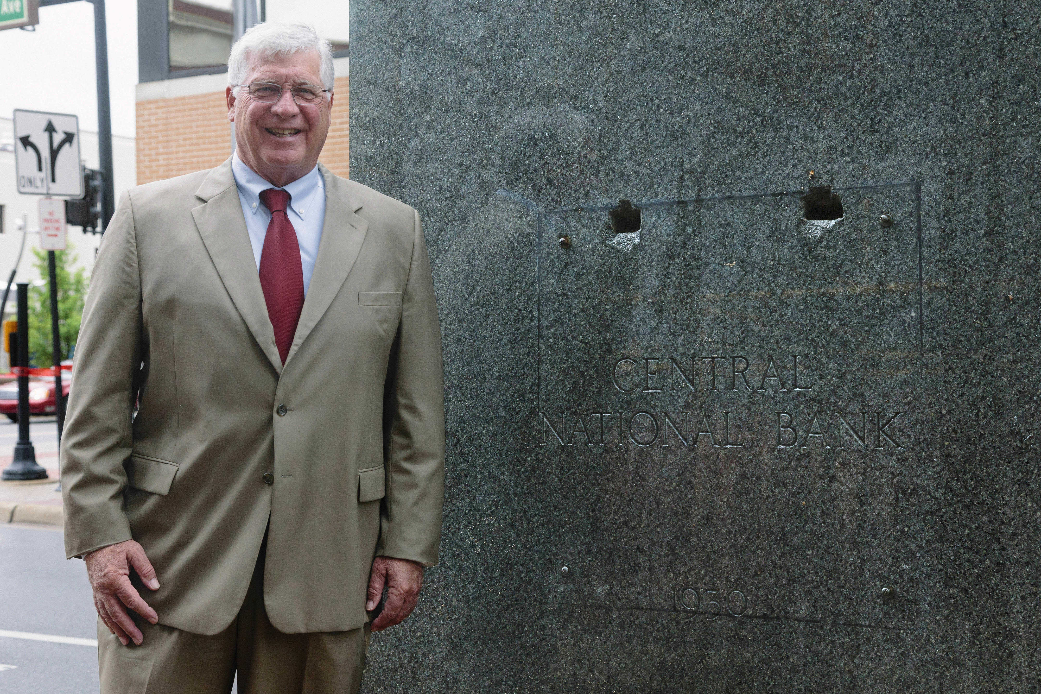 Roger Hinman in front of a Central National Bank granite slab on the exterior of the building